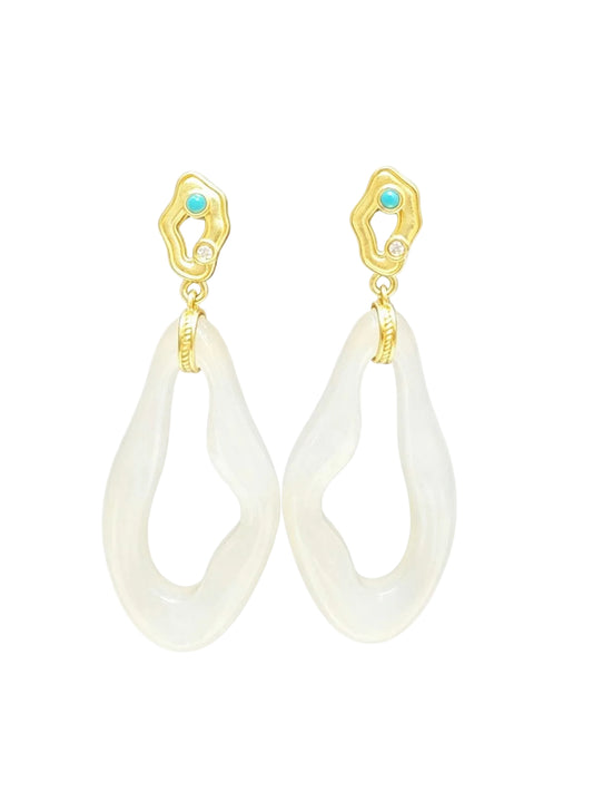 A pair of gold and white teardrop dangle earrings with small turquoise blue gemstone accents at the top, timeless.
